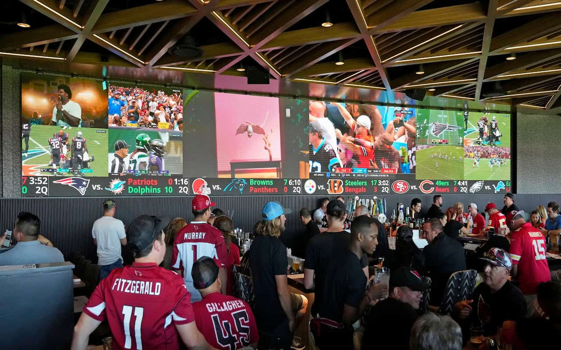 Crowded sports bar during NFL game with fans watching multiple TVs