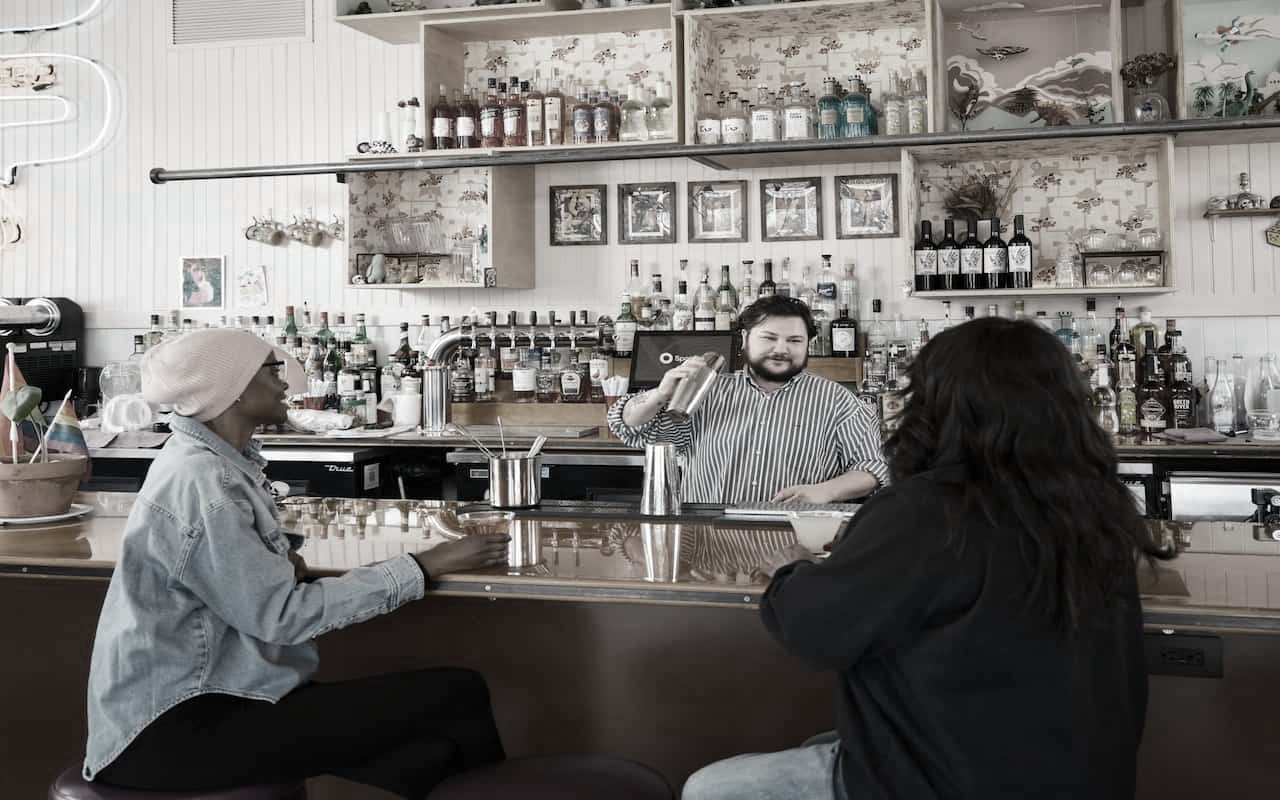 bartender with customers  Photo by SpotOn on Unsplash